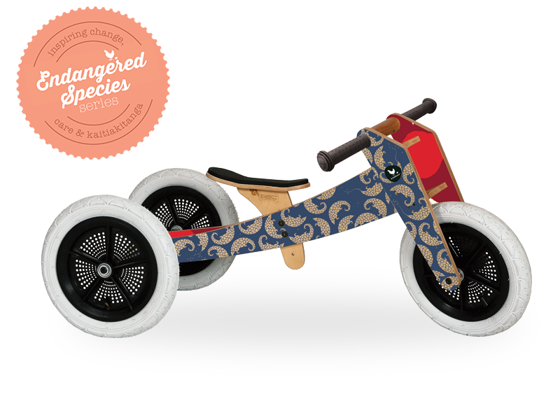 Dark blue and red wooden running trike with pangolin artwork on outside